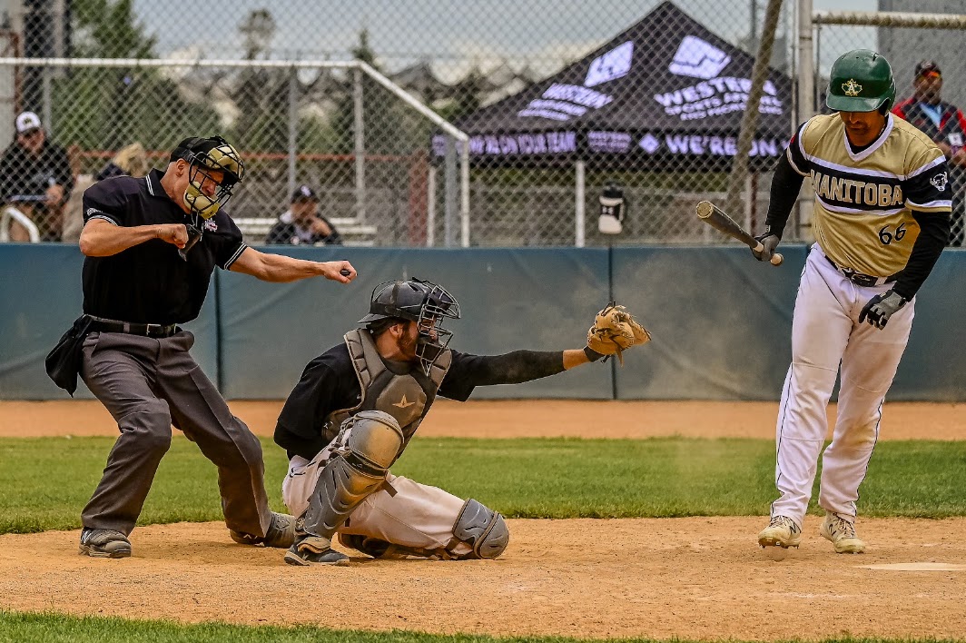 Umpire calling a strikeout at home plate as the batter walks away